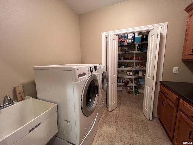 clothes washing area featuring washing machine and clothes dryer, a sink, and cabinet space