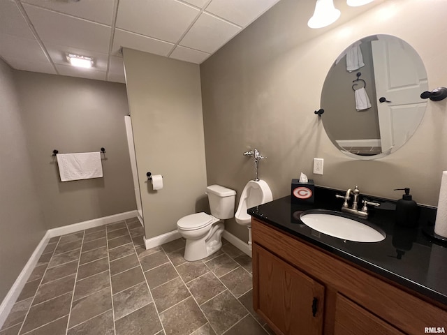 full bathroom featuring a paneled ceiling, toilet, vanity, and baseboards