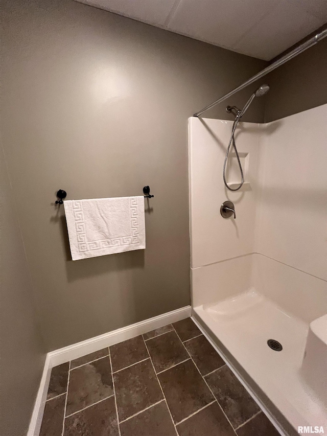 bathroom featuring a shower stall, baseboards, and tile patterned flooring