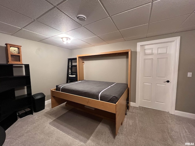 bedroom featuring a drop ceiling, carpet, and baseboards