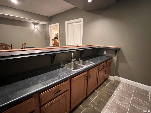 bar featuring baseboards, dark tile patterned flooring, a sink, and recessed lighting