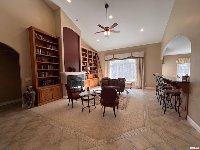 sitting room featuring arched walkways, plenty of natural light, and a glass covered fireplace