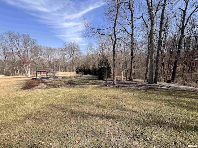 view of yard with a gazebo and a view of trees