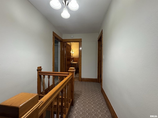 hallway with dark carpet, an upstairs landing, and baseboards