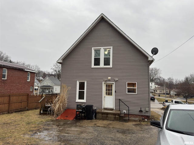 back of property featuring entry steps and fence