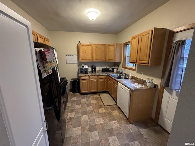 kitchen featuring white dishwasher, a sink, a healthy amount of sunlight, black fridge, and dark countertops