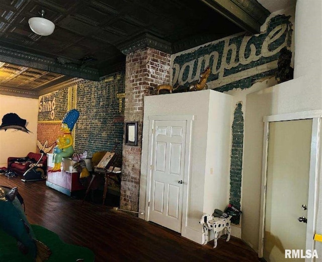 interior space with brick wall, an ornate ceiling, and wood finished floors