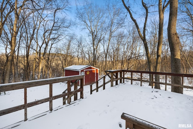 snow covered deck with a shed and an outbuilding
