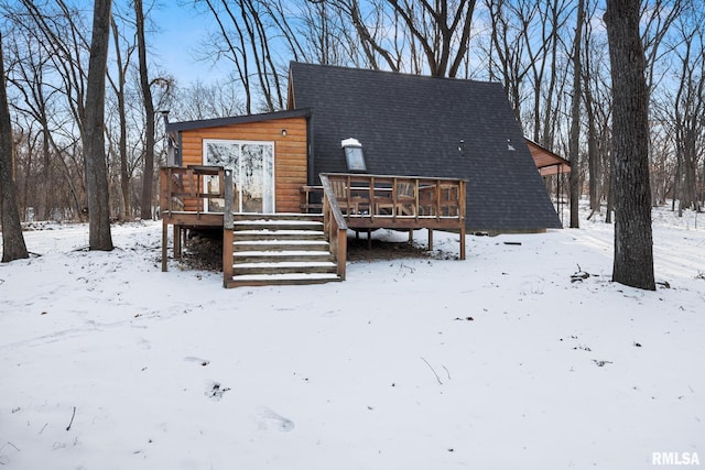 view of front of property featuring a deck, roof with shingles, and faux log siding