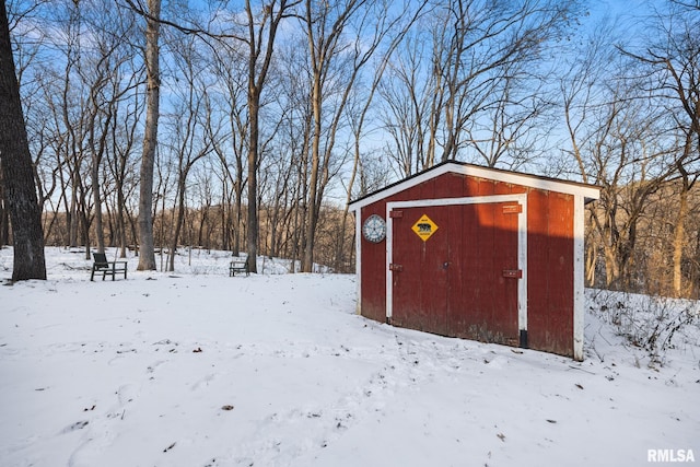 snow covered structure featuring a storage shed and an outbuilding