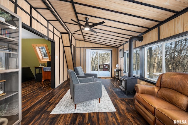 living area featuring plenty of natural light, lofted ceiling, a wood stove, and dark wood finished floors