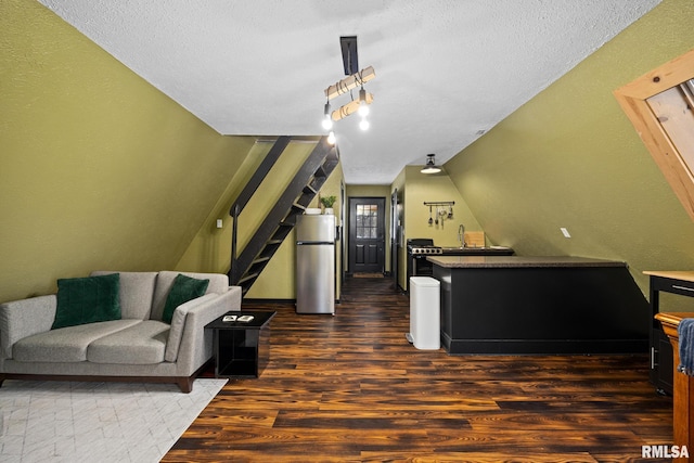living area featuring stairway, dark wood-style flooring, vaulted ceiling, a textured ceiling, and track lighting