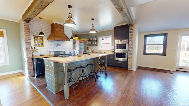 kitchen with double oven, beamed ceiling, custom exhaust hood, and open shelves