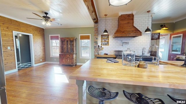 kitchen featuring custom range hood, wood counters, ornamental molding, and wood finished floors