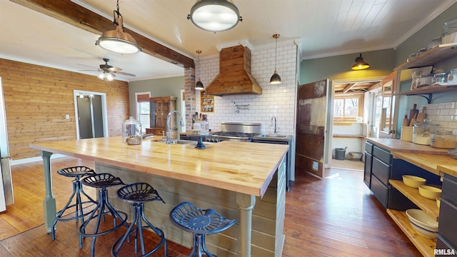 kitchen featuring open shelves, custom exhaust hood, wooden counters, and a wealth of natural light