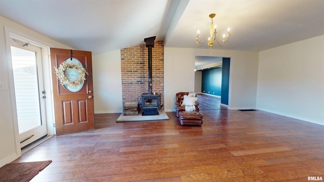 entryway featuring baseboards, wood finished floors, vaulted ceiling with beams, a wood stove, and a chandelier