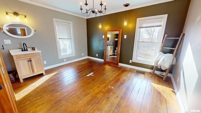 interior space featuring crown molding, a notable chandelier, visible vents, baseboards, and hardwood / wood-style flooring