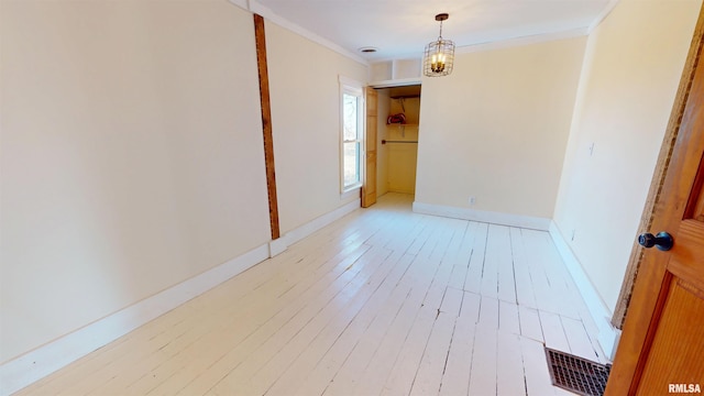 unfurnished room with a notable chandelier, visible vents, light wood-style floors, ornamental molding, and baseboards