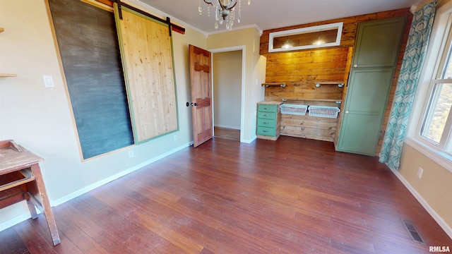 unfurnished bedroom featuring a barn door, visible vents, baseboards, dark wood finished floors, and crown molding