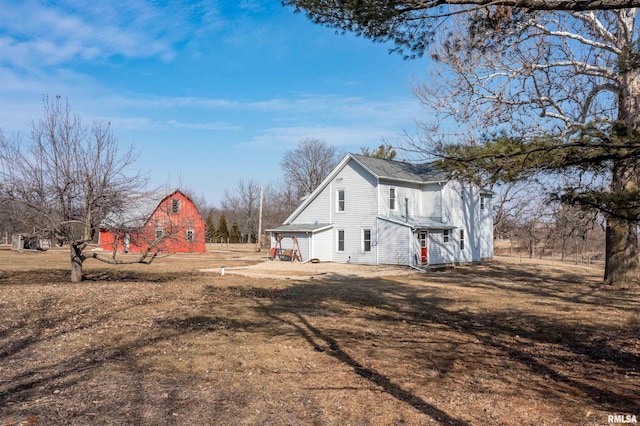 view of home's exterior with dirt driveway, an outbuilding, a barn, and a garage