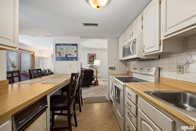 kitchen with tasteful backsplash, visible vents, a sink, butcher block countertops, and white appliances