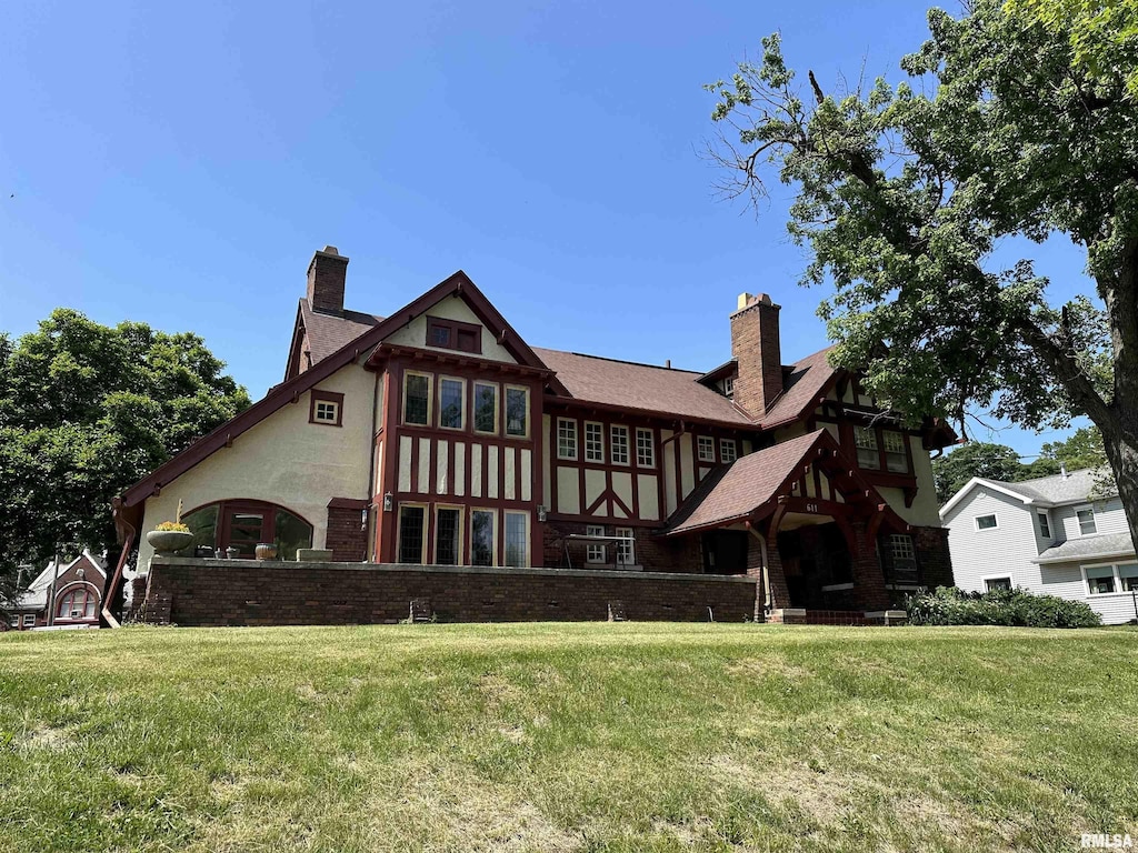 exterior space featuring a front lawn, a chimney, and brick siding