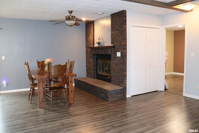 dining room featuring a ceiling fan, a fireplace, baseboards, and wood finished floors