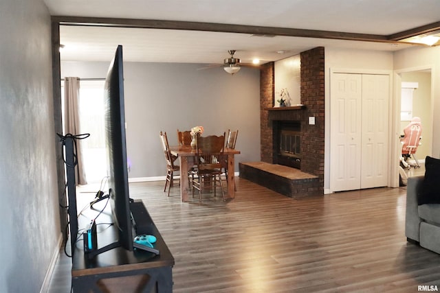 dining space with baseboards, a ceiling fan, wood finished floors, beamed ceiling, and a fireplace