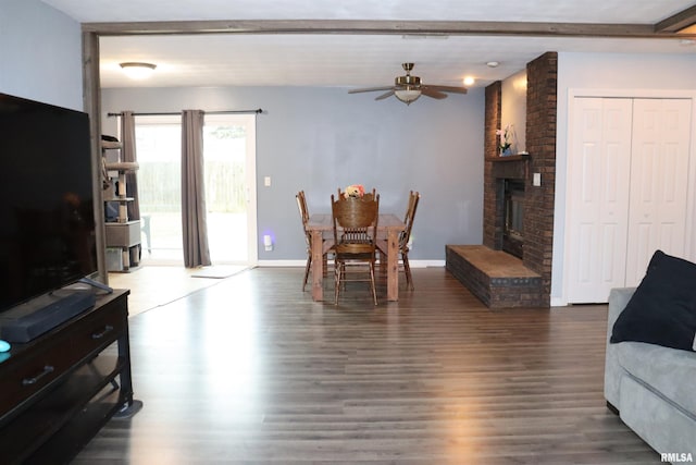 dining room featuring a brick fireplace, ceiling fan, baseboards, and wood finished floors