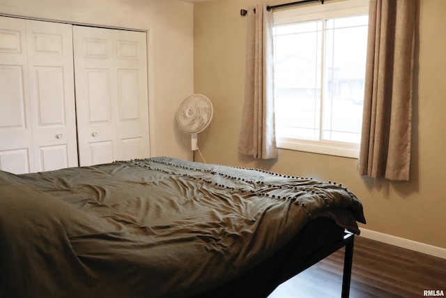 bedroom featuring a closet, multiple windows, baseboards, and wood finished floors