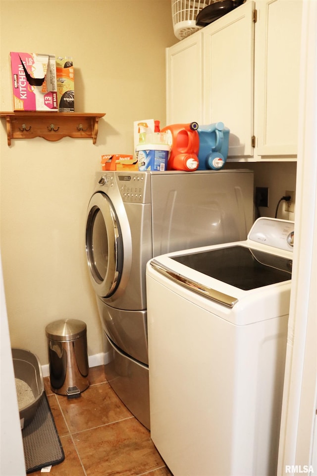 laundry area with washer and clothes dryer, light tile patterned flooring, cabinet space, and baseboards