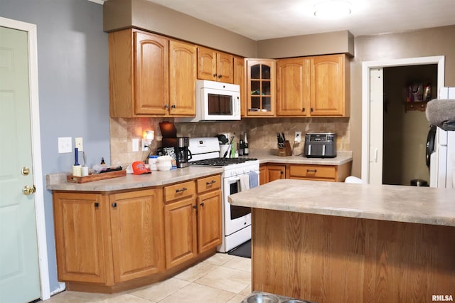 kitchen with light tile patterned floors, white appliances, light countertops, decorative backsplash, and glass insert cabinets