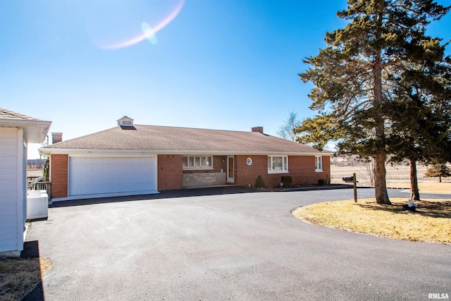 single story home with driveway, a garage, and brick siding