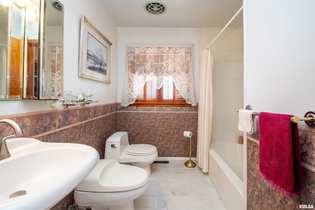 bathroom with visible vents, wainscoting, toilet, shower / bath combination with curtain, and a sink