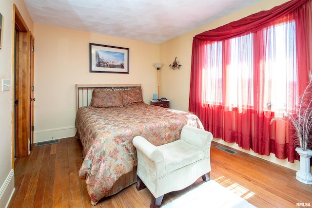 bedroom featuring visible vents, baseboards, and hardwood / wood-style flooring