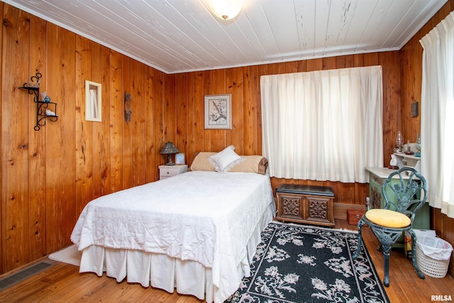 bedroom featuring wooden ceiling, visible vents, wood walls, and hardwood / wood-style floors