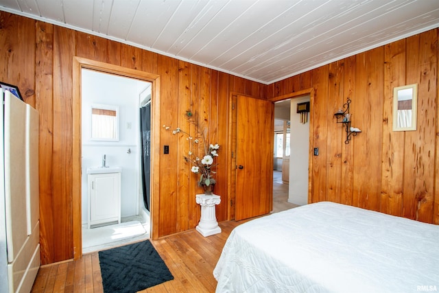 bedroom featuring crown molding, hardwood / wood-style floors, and wooden walls