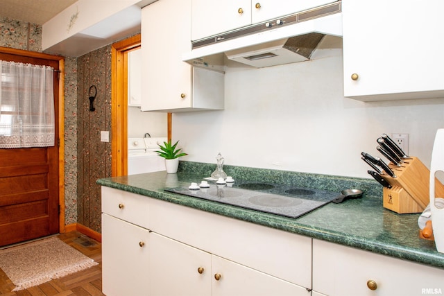 kitchen featuring black electric cooktop, under cabinet range hood, white cabinets, washer and clothes dryer, and dark countertops