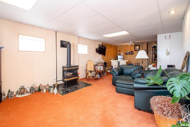 living area with a wealth of natural light, carpet, a wood stove, and a drop ceiling