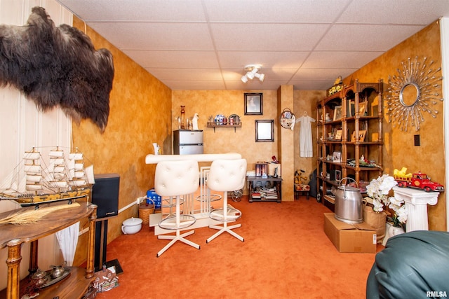 interior space with a paneled ceiling and carpet