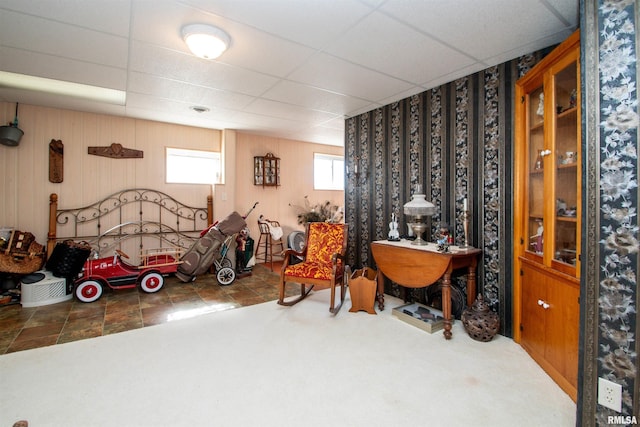 interior space featuring wood walls, carpet flooring, and a paneled ceiling