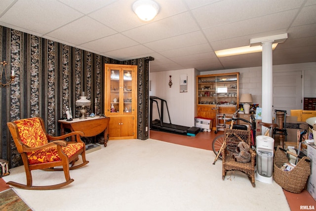 living area with a paneled ceiling and decorative columns