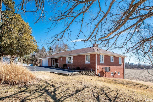 exterior space featuring central AC, brick siding, a chimney, and driveway