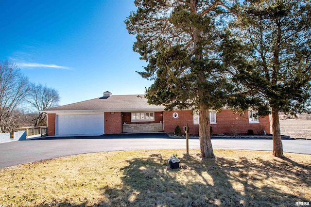 single story home with a garage, driveway, and brick siding