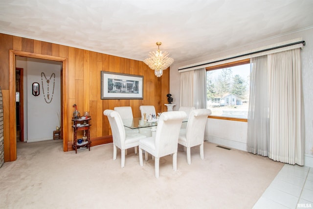 dining room featuring wooden walls, ornamental molding, visible vents, and a notable chandelier