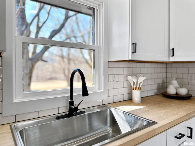 room details featuring white cabinets, a sink, and backsplash