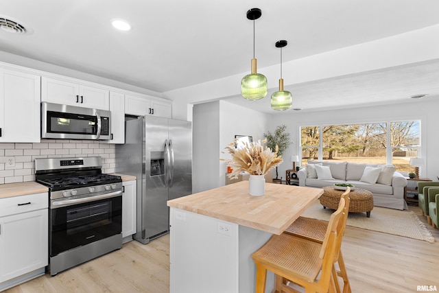 kitchen with tasteful backsplash, visible vents, open floor plan, stainless steel appliances, and light wood-style floors