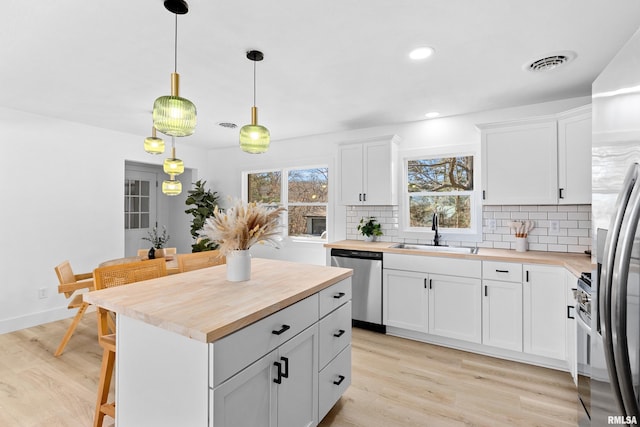 kitchen with stainless steel appliances, tasteful backsplash, visible vents, wooden counters, and a sink