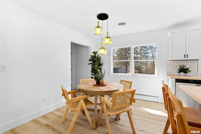 dining room with baseboards, baseboard heating, visible vents, and light wood-style floors