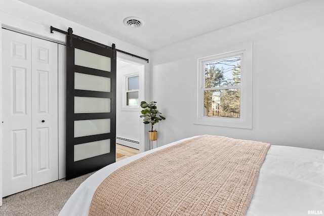 bedroom with a barn door, a baseboard radiator, carpet flooring, visible vents, and a closet